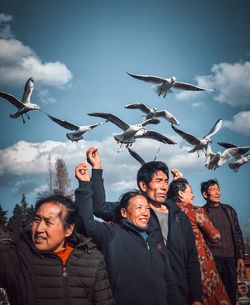 Young man and woman with birds against sky