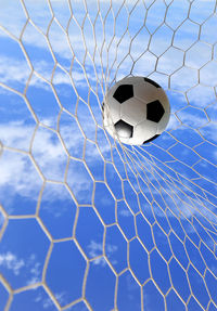 Soccer ball hitting in goal post against blue sky