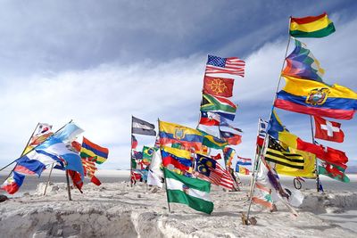 Colorful flags on rock against cloudy sky