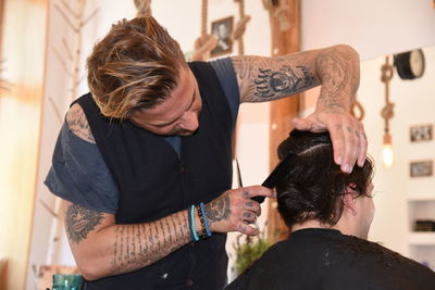 Rear view of barber combing hair in shop