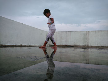 Side view of girl walking on terrace against sky