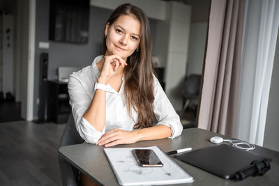 Young woman using mobile phone at table