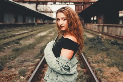 Portrait of beautiful woman standing on railroad track