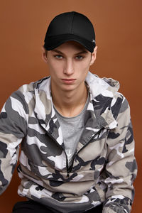 Portrait of young man sitting against gray background