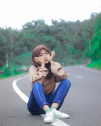 Portrait of a young woman sitting on road