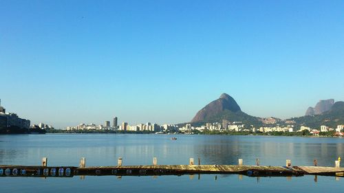 Scenic view of sea and mountains against clear blue sky