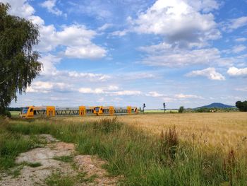 Scenic view of grassy field against cloudy sky