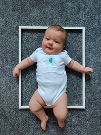 A little girl is lying on the floor in a photo frame and smiling