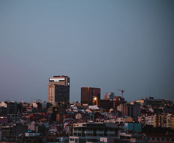 Buildings in city against clear blue sky