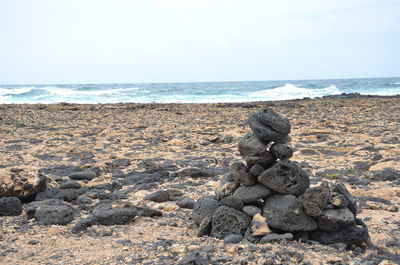 Stack of pebbles on beach against sky