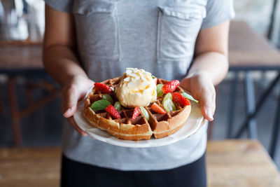 Midsection of woman holding waffle