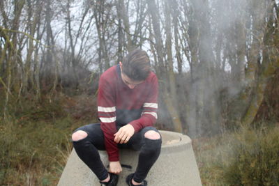 Full length of young woman sitting in forest