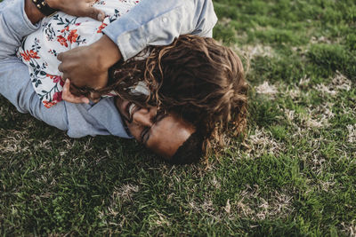 Happy father laying on grass playing with young daughter