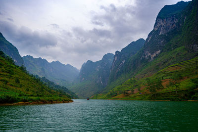Scenic view of lake by mountains against sky