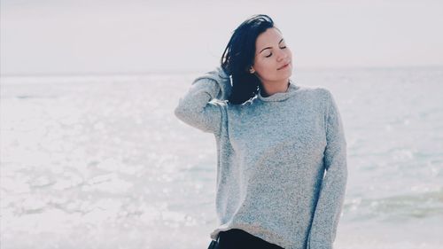 Young woman standing at beach against clear sky