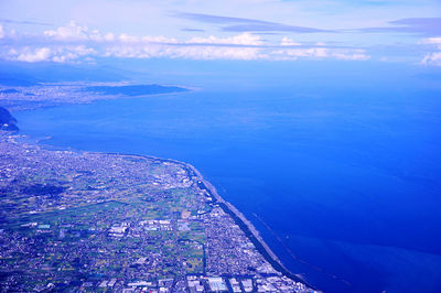 Aerial view of city by sea against sky