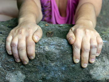 Close-up of woman hand on rock