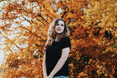 Portrait of smiling young woman in autumn tree