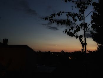 Silhouette trees and buildings against sky at sunset