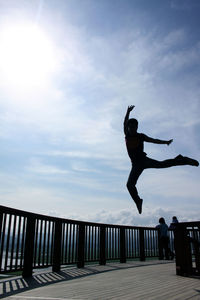 Low angle view of man jumping against sky