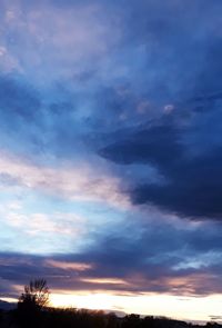 Low angle view of silhouette trees against dramatic sky