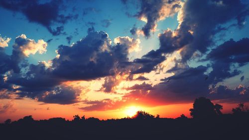 Low angle view of silhouette trees against dramatic sky