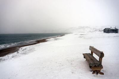 Solitude. a wooden bench overlooking the winter sea on a snow covered beach day