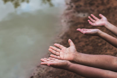 Cropped hands gesturing against lake