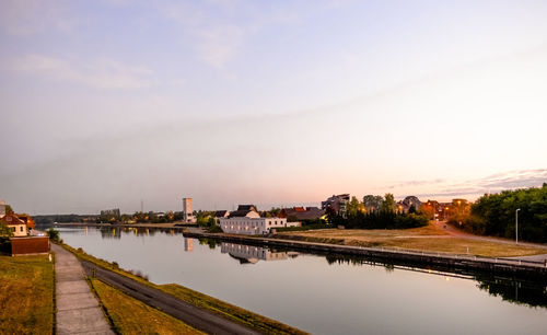 Scenic view of river by buildings against sky