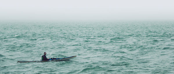Man kayaking in sea against sky
