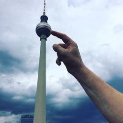 Low angle view of communications tower against cloudy sky