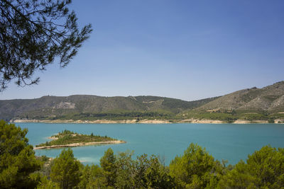 Scenic view of lake and mountains against clear blue sky