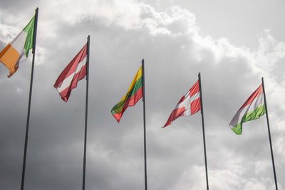 Low angle view of flags against cloudy sky