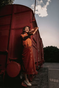 Woman standing against wall against sky