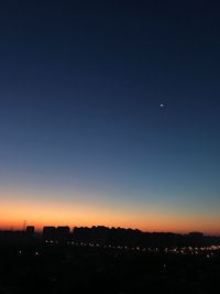 Silhouette cityscape against clear sky at night