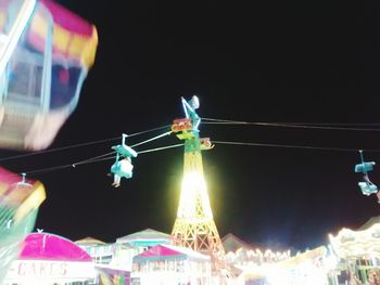 Low angle view of illuminated rides in traveling carnival against sky at night