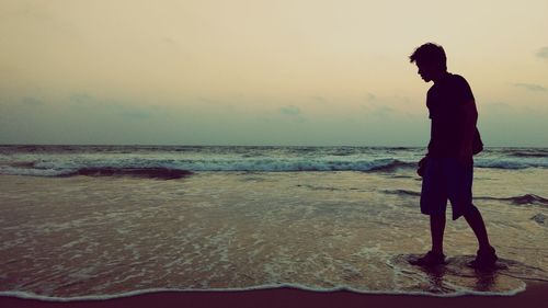 Full length of young man standing on shore at beach