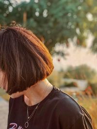 Woman with brown hair against trees