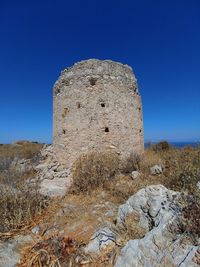 Low angle view of stone wall against clear blue sky