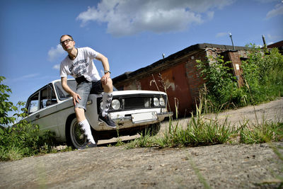 Man standing by car against sky