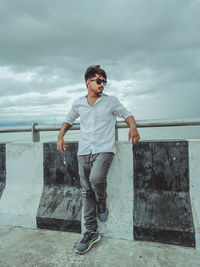 Young man wearing sunglasses standing against sky