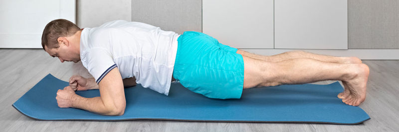 A strong, healthy man with muscles, training at home in the plank position. fitness at home. banner.
