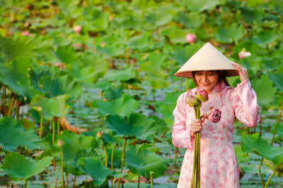 Woman wearing hat standing against plants