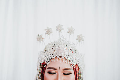 Close-up portrait of woman against white wall