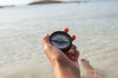 A woman's hand holds a compass in the sea