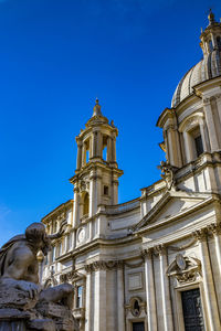 Low angle view of statue against building against clear blue sky