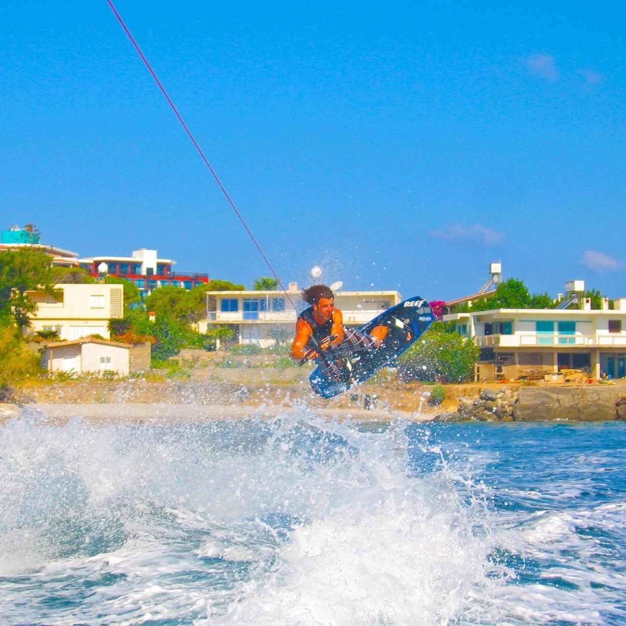 water, waterfront, leisure activity, lifestyles, building exterior, blue, motion, built structure, architecture, clear sky, men, sea, splashing, enjoyment, vacations, wave, day, fun