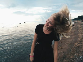 Beautiful woman tossing hair while standing at beach