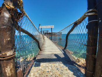 Empty footbridge against clear blue sky