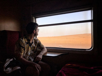 Young man looking through window while sitting in car